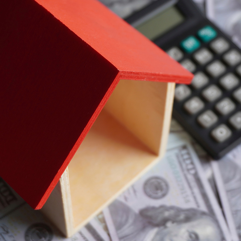 Close up image of toy house, calculator and money.
